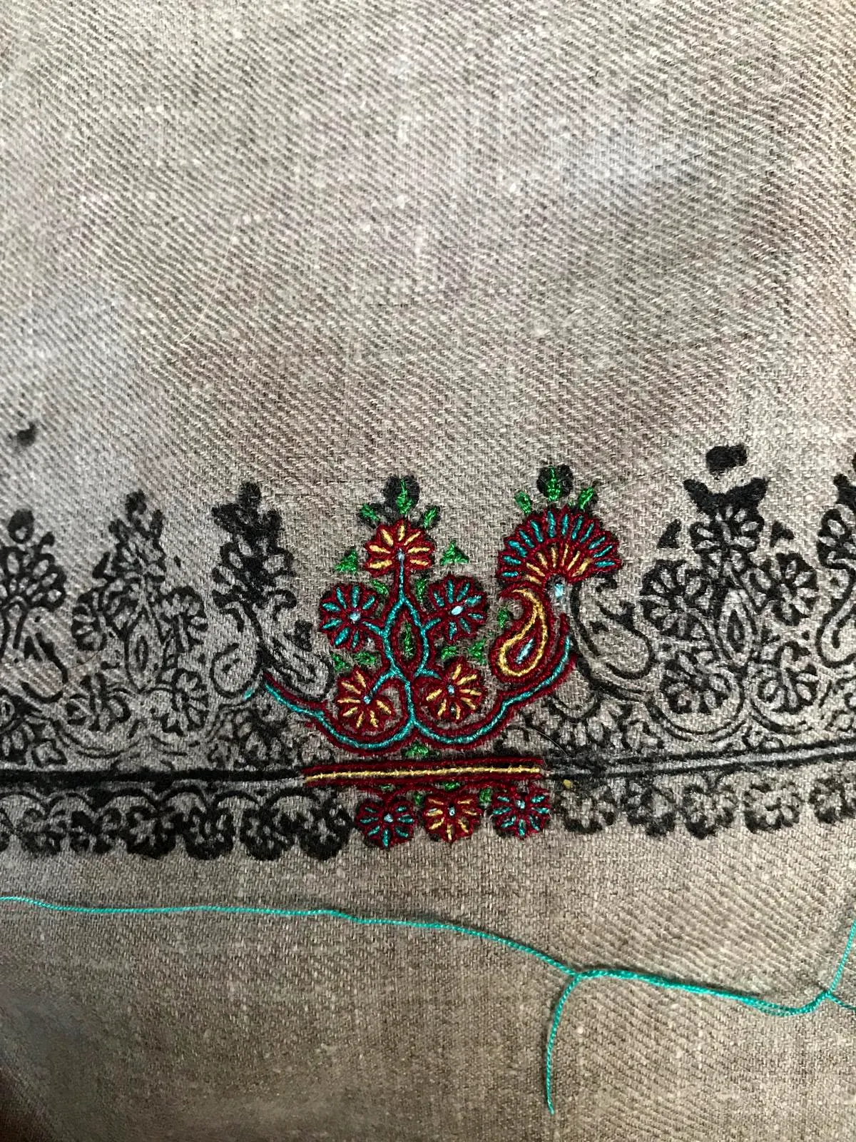 A coloured motif embroidered into a black printed border on grey pashmina.