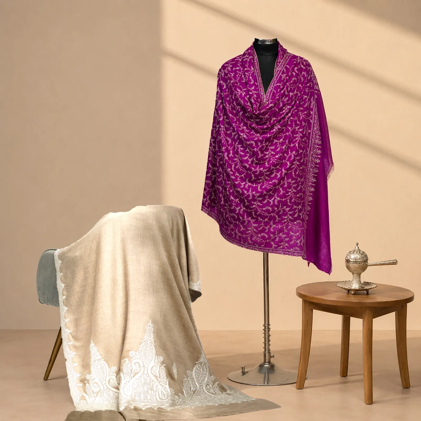 Magenta shawl with tonal embroidery across the ground, a cream embroidered shawl on a chair behind.