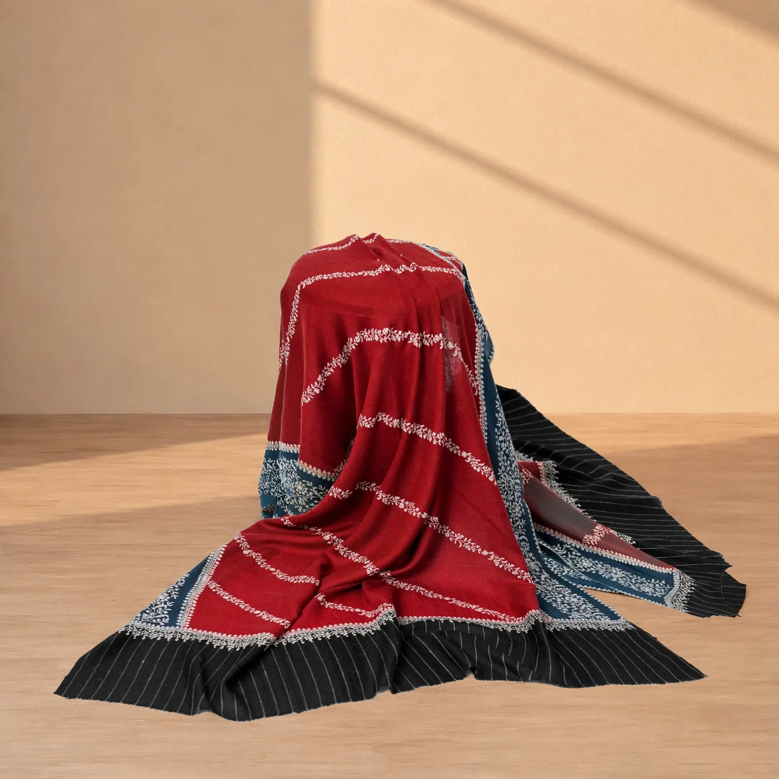 Deep crimson shawl with pale scrolling motifs and a pleated black and blue border.