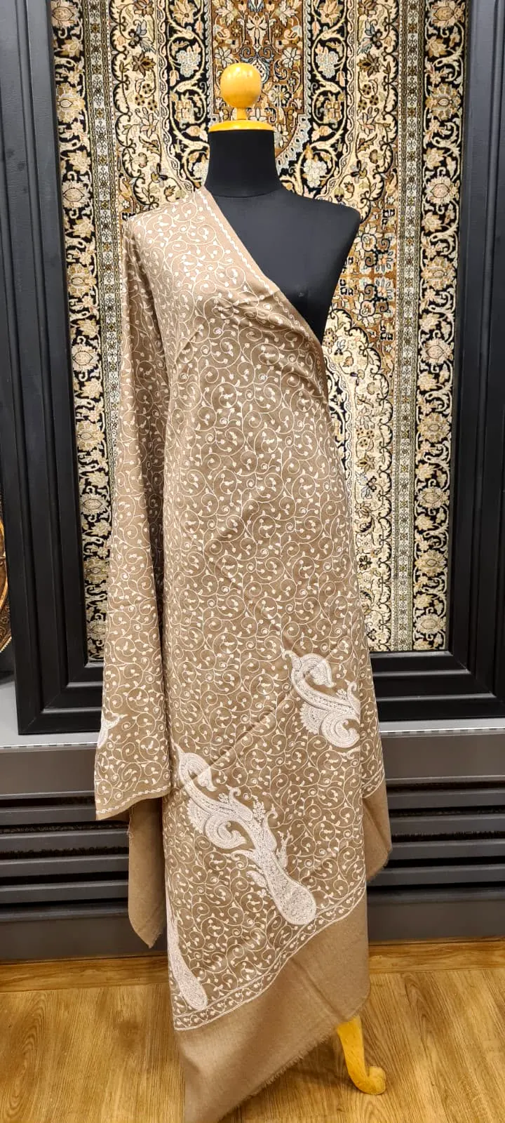 Beige shawl on a stand with a large ivory paisley worked across one corner.