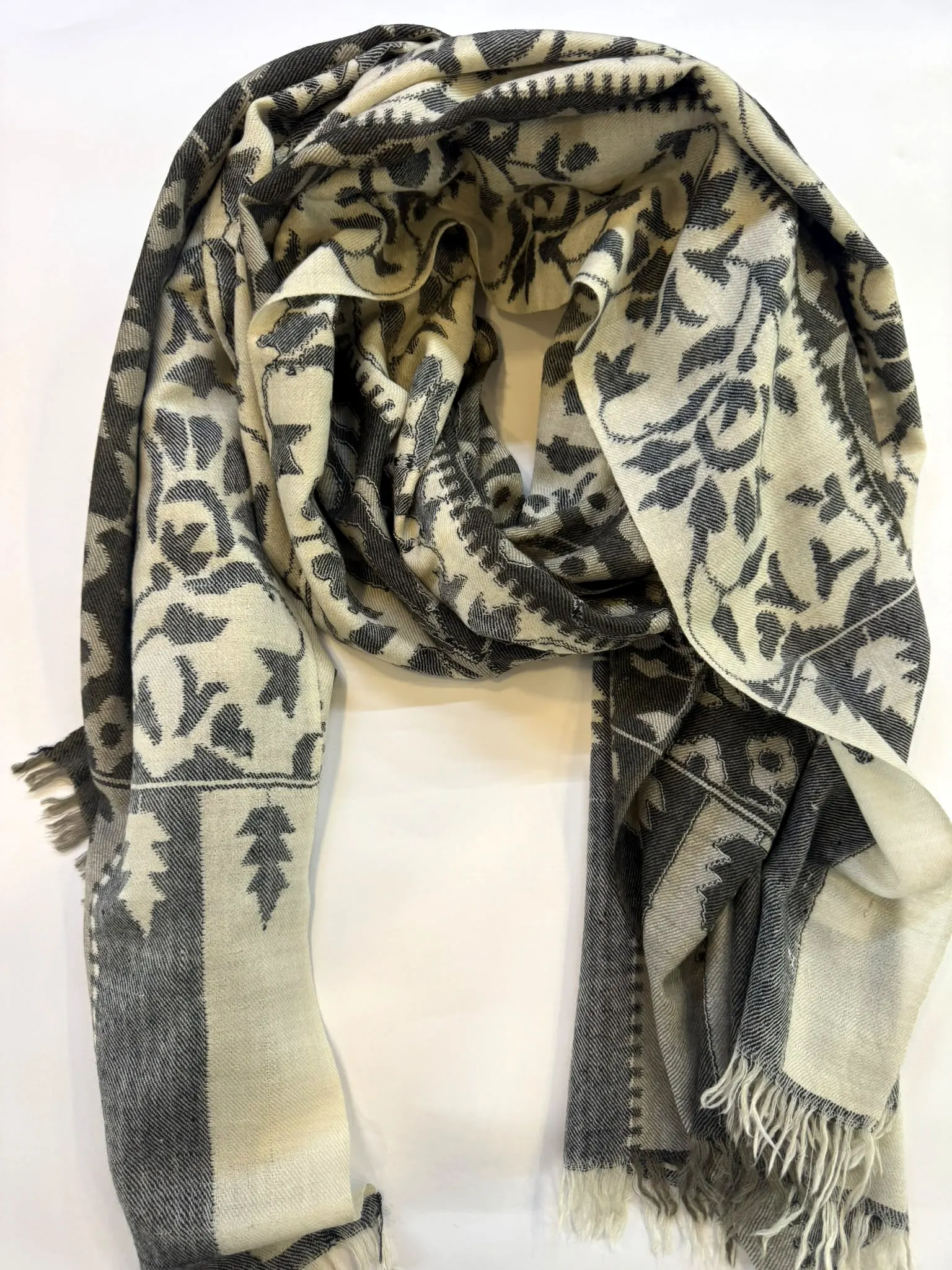 Ivory kani stole woven with charcoal leaves and vines, with grey striped ends and a fringe.