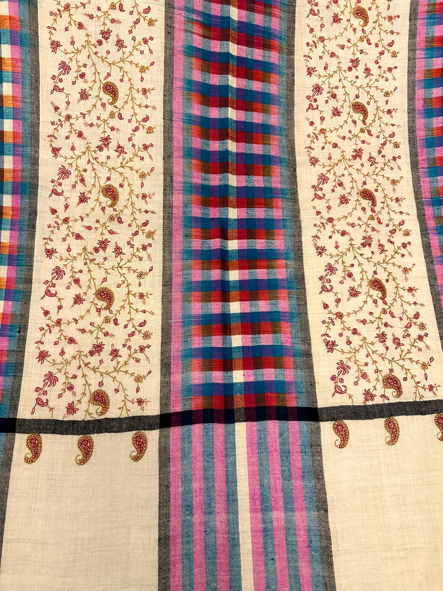 Flat view of the same shawl, showing the plaid band between two panels of vine needlework.