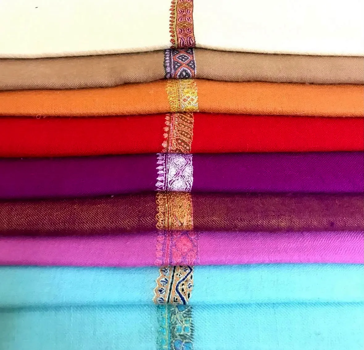 Folded stoles in jewel tones, each with a narrow embroidered border.