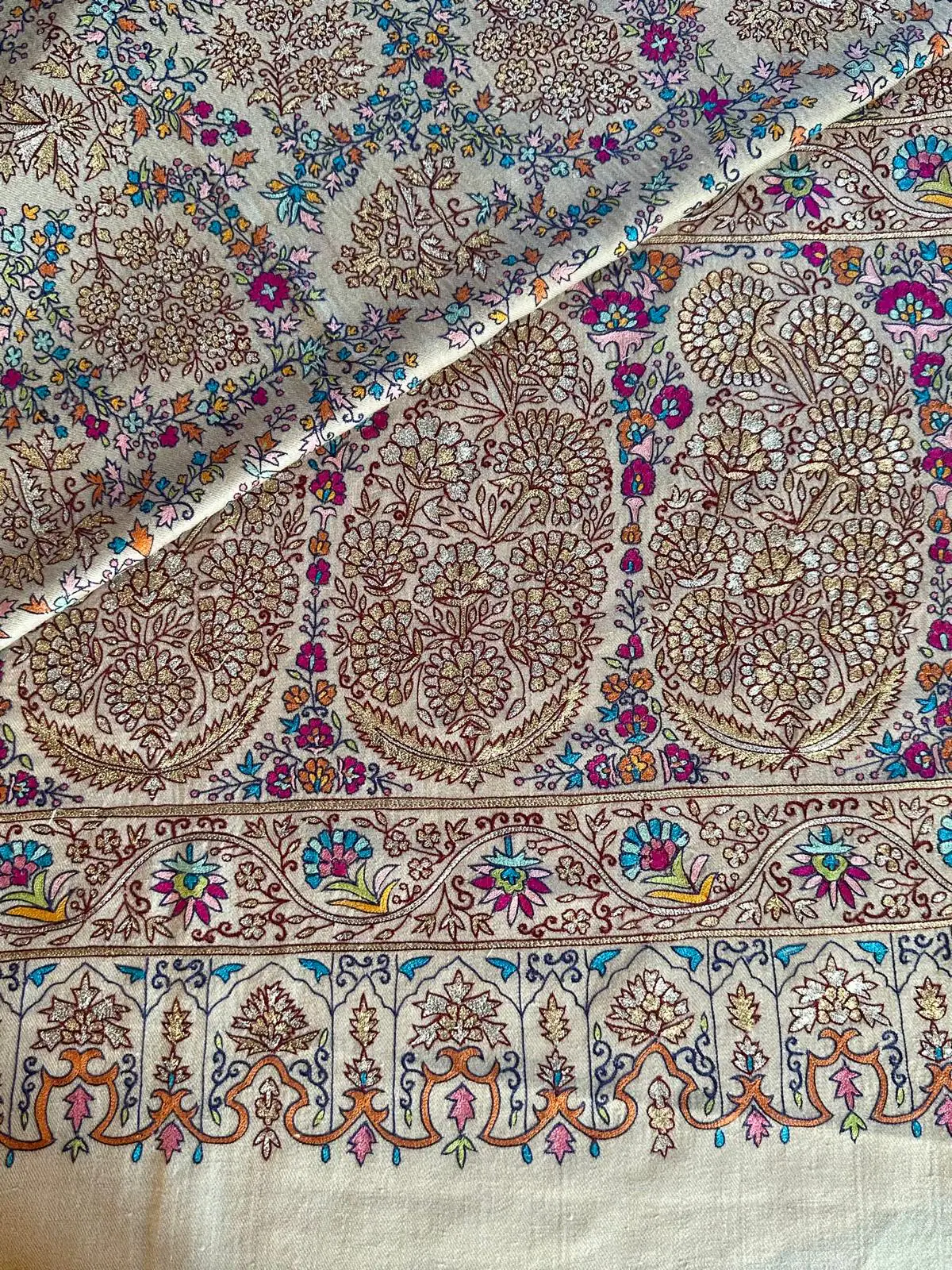 Cream kalamkari shawl with gold medallions, multicoloured flowers and a scalloped border in orange, blue and pink.