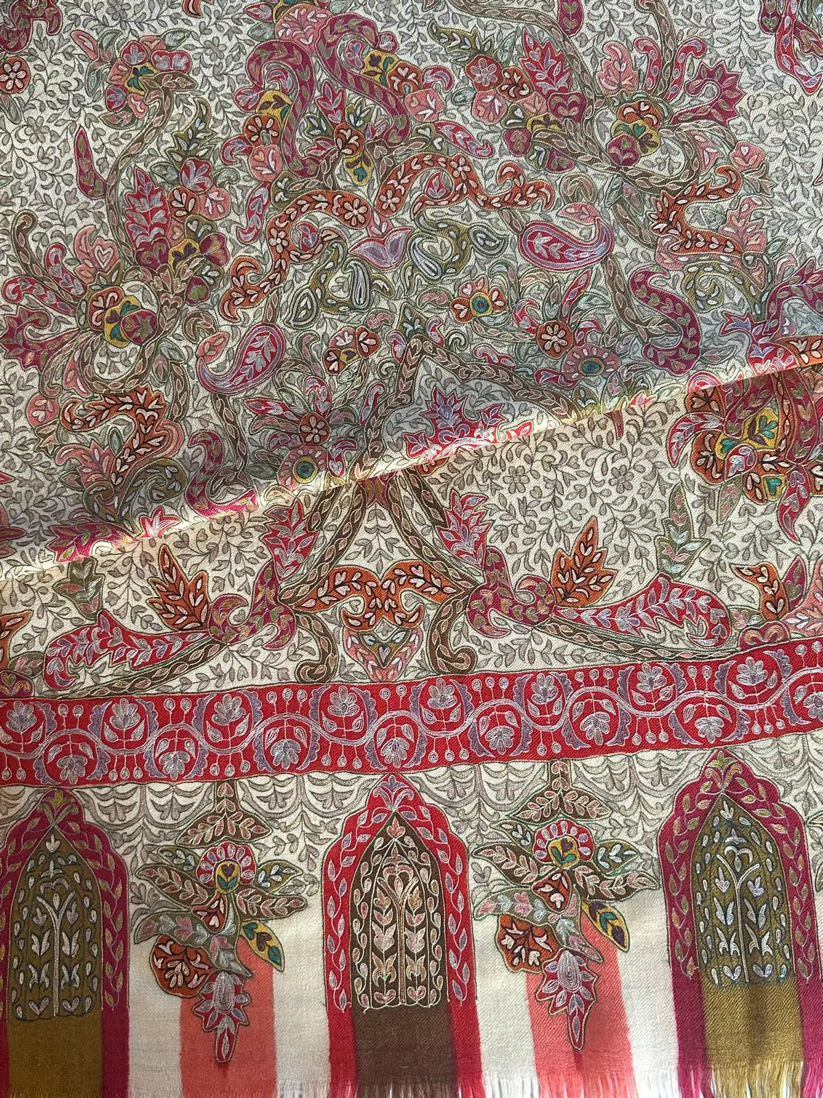 Ivory kalamkari shawl with rose, olive and green floral pattern above a red band and arched border panels.