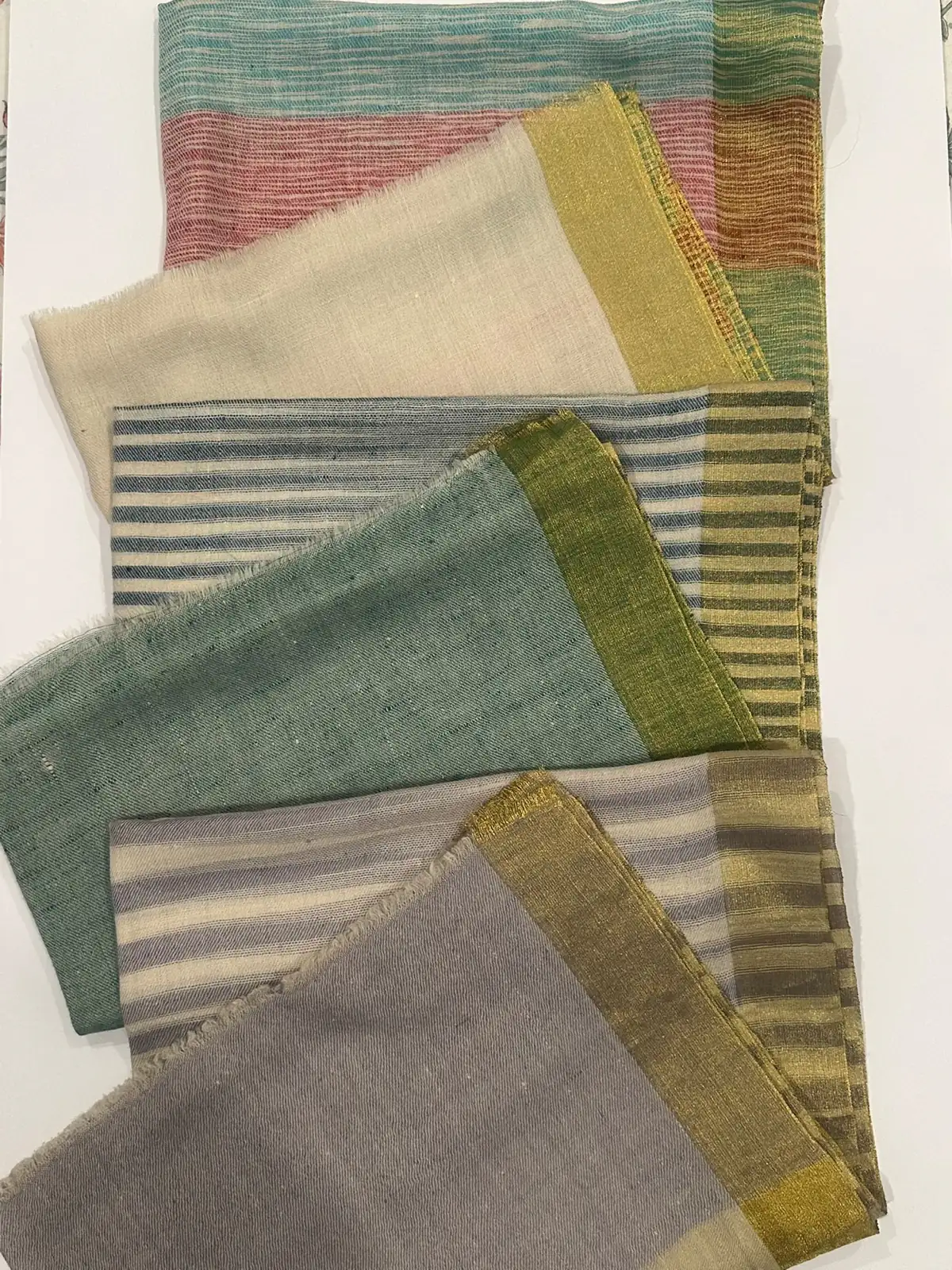 Stoles in woven stripes and shaded colour, laid one over another.