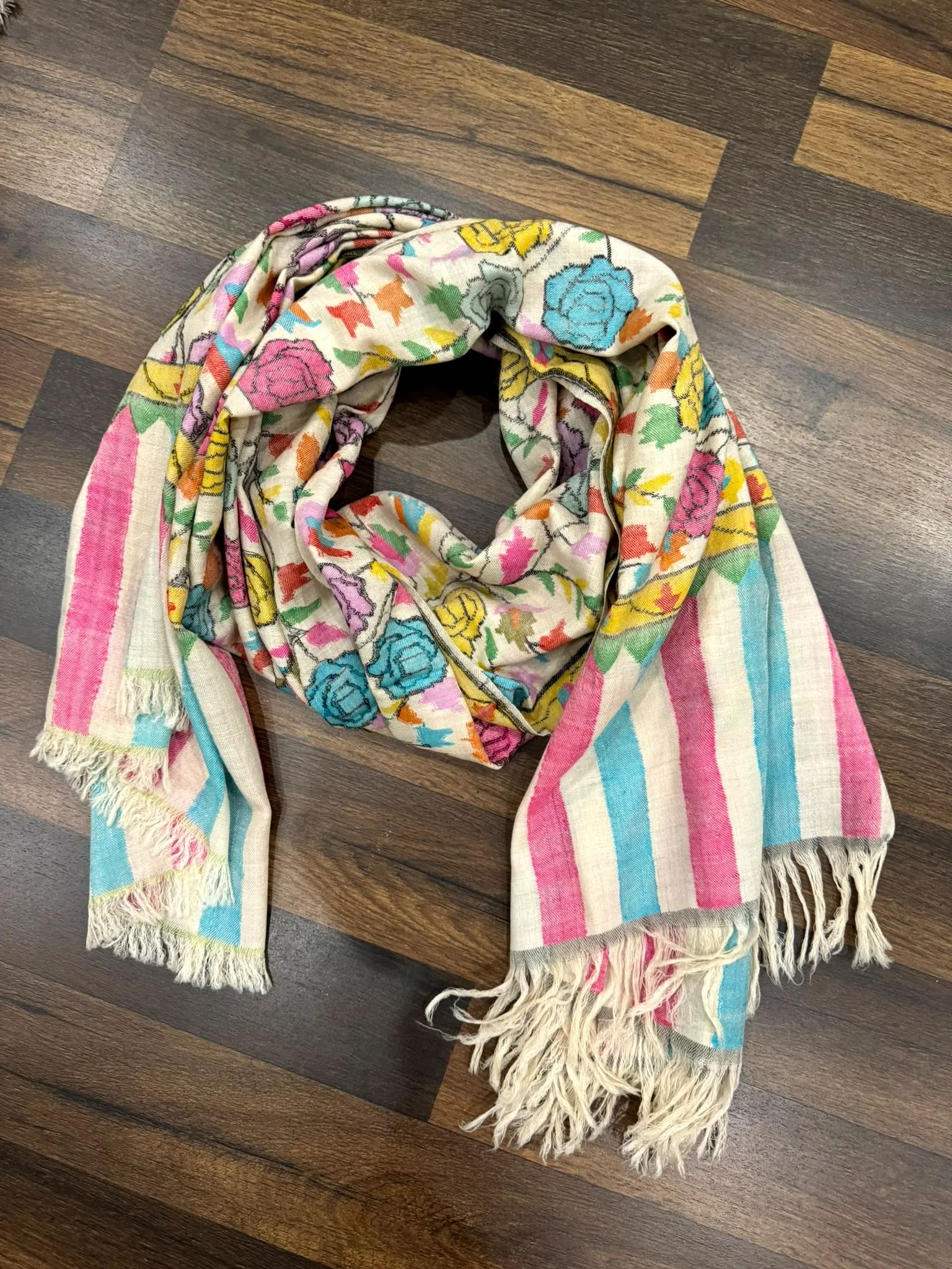Ivory kani stole with large pastel roses and pink and aqua striped ends, on a wooden floor.