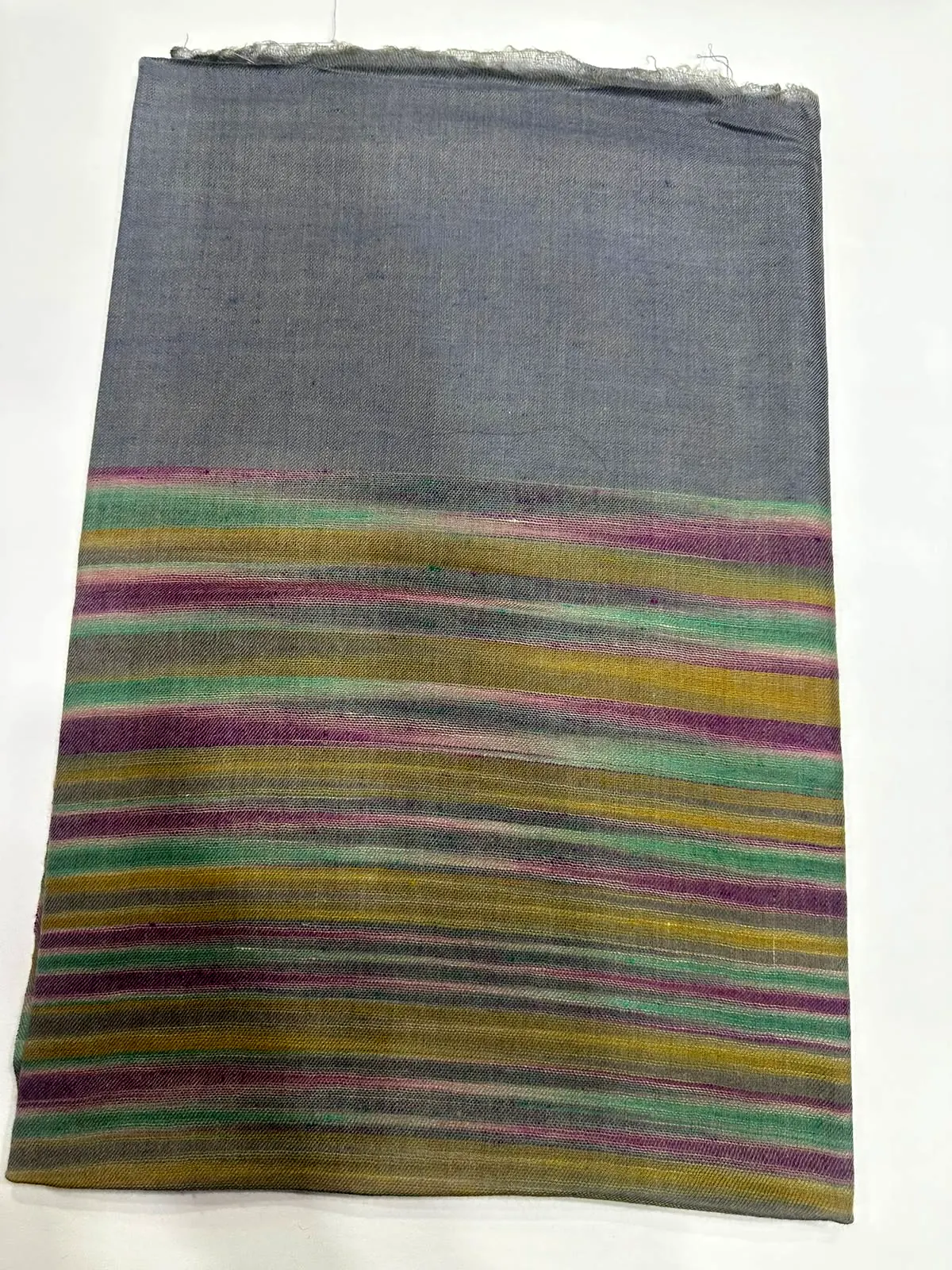 Folded shawl with a slate upper half and fine rainbow stripes below.