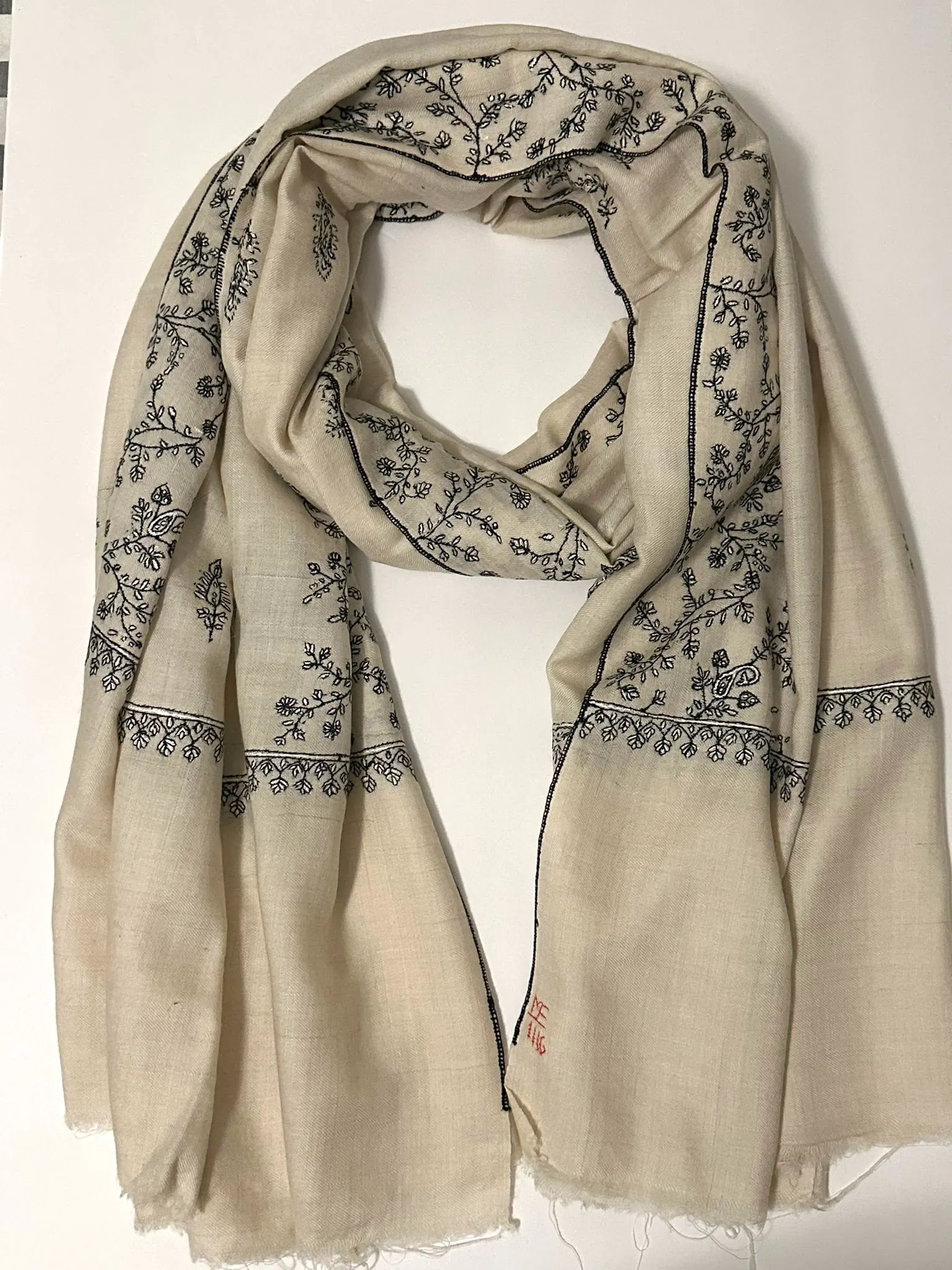 Pale stone stole with black floral needlework along the borders.