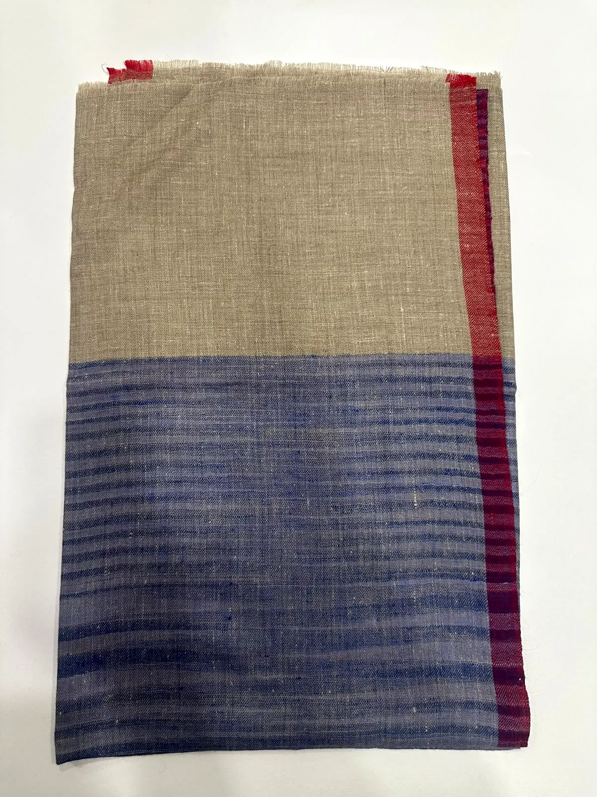 Folded shawl with a stone upper half and an indigo striped lower half.