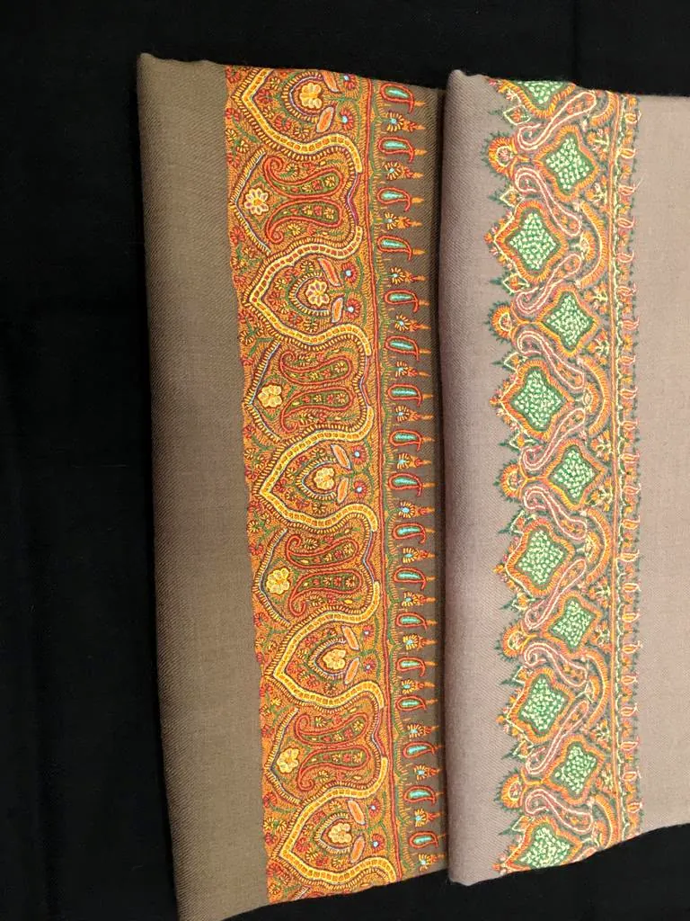 Two taupe shawls side by side, each with a broad orange and green needlework border.